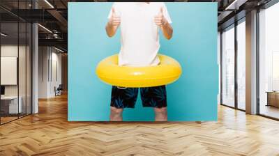 Full lenght Young handsome man with inflatable yellow ring and snorkel with thumbs up isolated on green background Wall mural